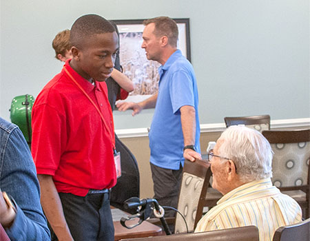 young man talking with seated man