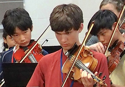 three boys playing violin
