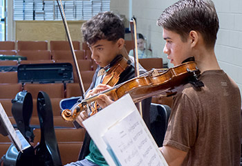 Two young men playing violins