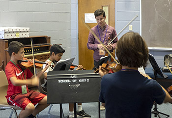 young man helping youngsters learn music