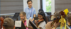 Girl helping children play violin