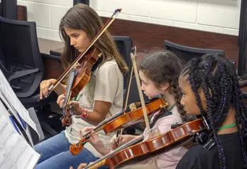 three girls playing violins
